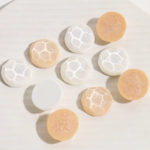 Close-up of circular resin shoe buckles with honeycomb texture in white and apricot