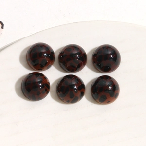 Close-up of six leopard print acrylic half-beads for DIY jewelry making and earrings