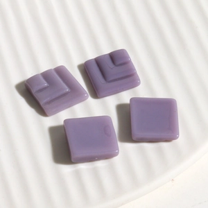 Macro detail of violet square resin accessories for DIY jewelry on a white ceramic tray