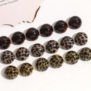 Detailed macro view of hemispherical leopard print acrylic charms in three varied colors