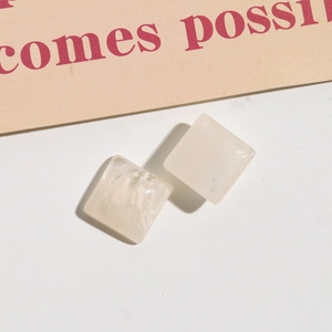 Dettaglio componenti per orecchini quadrati in resina con trama marmorea bianco crema