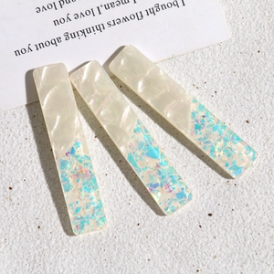 Détail de barrettes rectangulaires en acrylique avec nacre blanche et paillettes bleues
