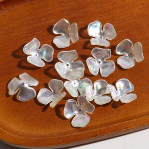 Iridescent white acrylic clover flower beads for DIY jewelry making on wooden tray