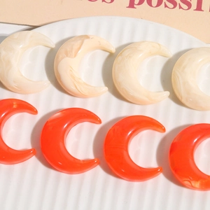Macro shot of crescent moon resin charms featuring marble texture in white and orange