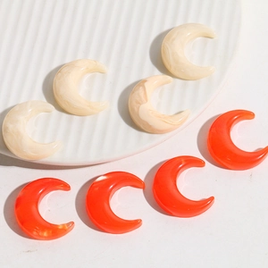 Detail of crescent moon resin charms in marble white and bright orange for DIY jewelry
