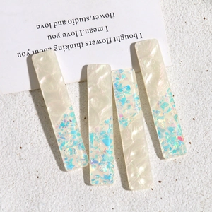 Détail de barrettes rectangulaires blanc nacré avec paillettes bleues irisées et chic