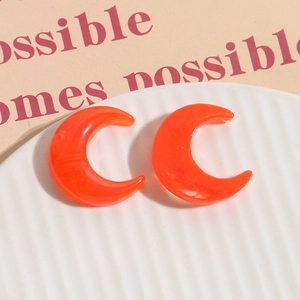 Close-up of bright orange resin crescent moon charms with marble texture and polished finish