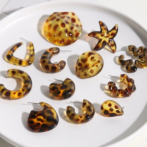 Collection of leopard print resin earrings in C-shape, star and wave designs on ceramic tray