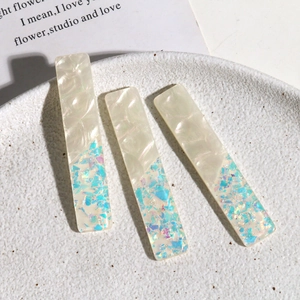 Détail de trois barrettes à cheveux en acrylique nacré sur une assiette en céramique
