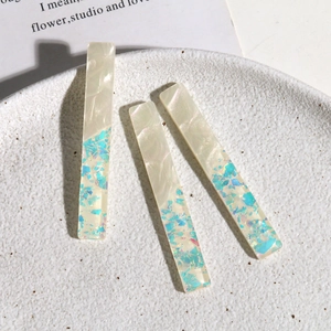 Détail macro de barrettes en acrylique blanc marbré avec paillettes sirène scintillantes