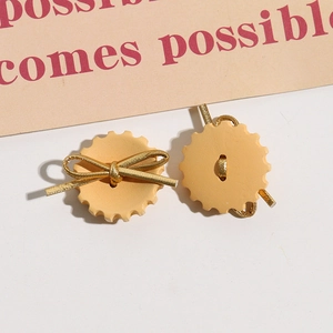 Detalle de botón de madera crema con lazo dorado para pendientes y accesorios