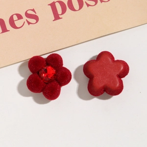 Makroaufnahme roter beflockter Blumenanhänger mit glitzernden Strasssteinen und Samttextur