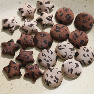 Close-up of leopard print star and round fabric buttons on a ceramic plate for DIY crafts