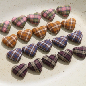 Detail of vintage heart-shaped plaid fabric buttons in assorted colors on a ceramic tray