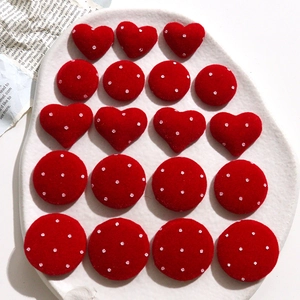 Macro detail of red velvet heart and round polka dot buttons on white ceramic plate