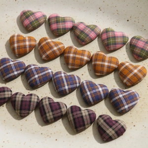 Macro detail of plaid heart fabric patches on a ceramic tray for DIY craft accessories