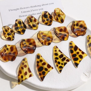 DIY leopard print resin leaf and petal charms displayed on a stone plate for jewelry making