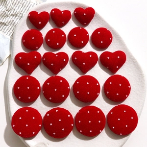 Close-up of red velvet heart and round polka dot DIY accessories on a ceramic plate