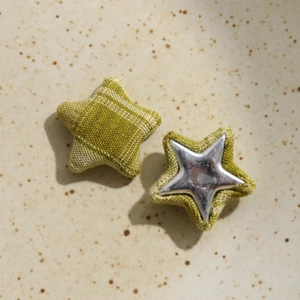 Dettaglio di bottoni in tessuto a forma di stella con motivo scozzese verde e inserto argento