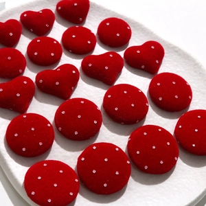 Macro shot of red flocked heart and round polka dot DIY accessories on a white plate