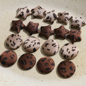 Close-up of leopard print fabric buttons in star and round shapes for DIY craft accessories