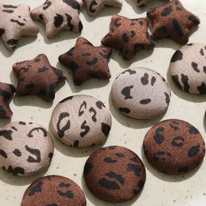Macro shot of leopard print fabric covered buttons and star patches for DIY craft