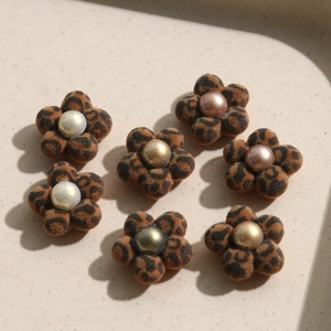 Macro detail of leopard flocking flower charms with pearl centers for DIY jewelry making