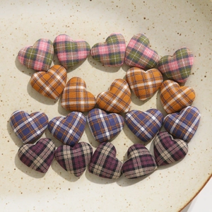 Macro detail of heart-shaped plaid fabric buttons in various colors on a ceramic tray