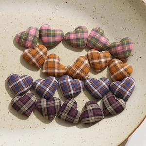 Close-up of colorful heart-shaped plaid fabric patches on a ceramic plate for DIY crafts