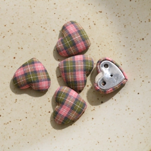 Detail of heart-shaped fabric buttons with pink plaid pattern and metal sewing base