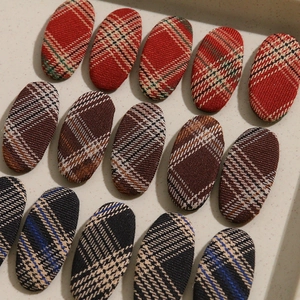 Détail de pinces à cheveux ovales en tissu écossais rouge, marron et bleu marine