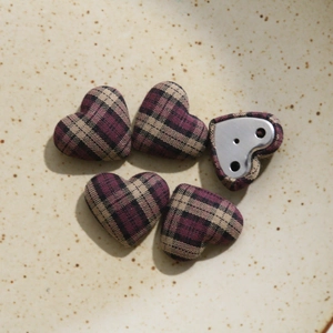 Close-up of heart-shaped plaid fabric buttons with silver metal sewing base on ceramic