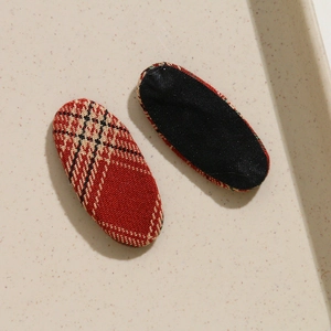 Vue macro de patchs ovales en tissu à carreaux rouges pour accessoires cheveux