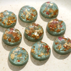 Vue macro de cabochons en résine faits main avec feuille d'or, fleurs et résille