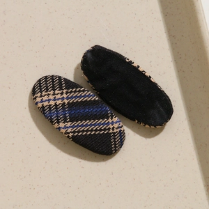 Détail de barrettes ovales en tissu à carreaux vintage bleu et beige sur plateau