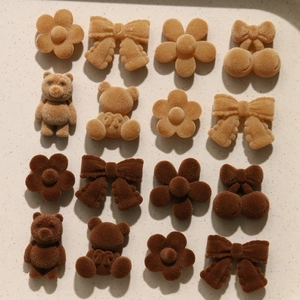Detailed view of DIY flocking plush bear and flower charms in warm coffee tones