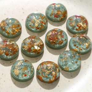Vue macro de cabochons en résine avec feuilles d'or, fleurs séchées et motifs nid d'abeille