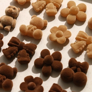 Macro shot of flocked bear, bow and flower accessories in coffee colors with velvet texture
