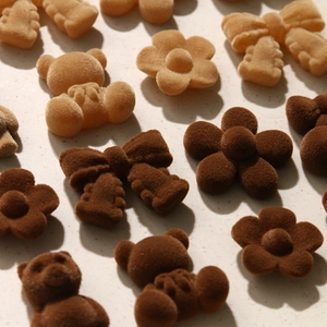 Macro shot of flocked bear, flower, and bow charms for DIY accessories in brown tones