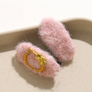 Close-up of pink plush hair clips featuring golden Kitty-shaped metal embellishments