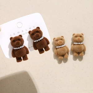 Close-up of teddy bear earrings with flocking texture and pearl necklace details
