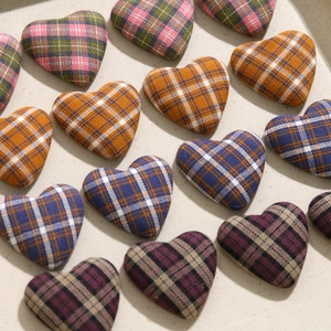 Vista macro di vari bottoni in tessuto a quadri a forma di cuore per gioielli DIY