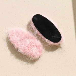 Detail of pink plush oval hair clip accessories showing wool texture and black backing