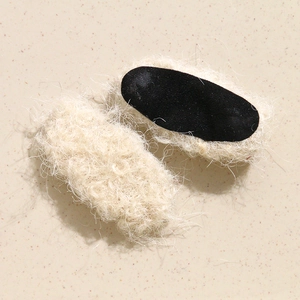 Detail view of plush beige oval hair clips with soft faux shearling texture and fabric base