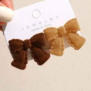 Close-up of brown flocked bow jewelry showing soft velvet texture and warm vintage style