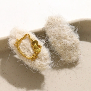Detail of plush off-white knitted hair clip featuring a gold Hello Kitty metal frame logo