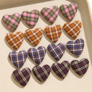 Dettaglio di sedici bottoni in tessuto scozzese a forma di cuore in quattro colori vintage