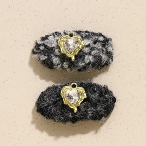Detail of tweed hair clips featuring golden heart pendants with sparkling rhinestones