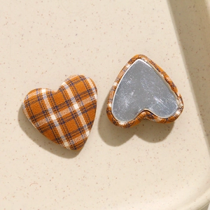 Dettaglio fronte e retro dei bottoni a cuore in tessuto scozzese arancione e metallo