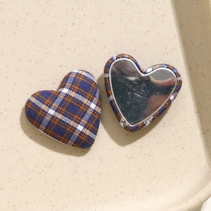 Dettaglio del bottone in tessuto scozzese blu a forma di cuore con retro a specchio